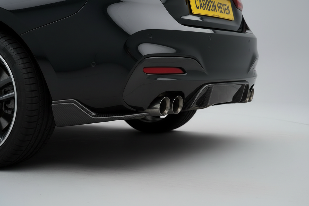 Close-up rear three-quarter view of a black car showing the rear bumper, dual chrome exhaust pipes, side skirt, and a yellow license plate that reads CARBON HEAVY.