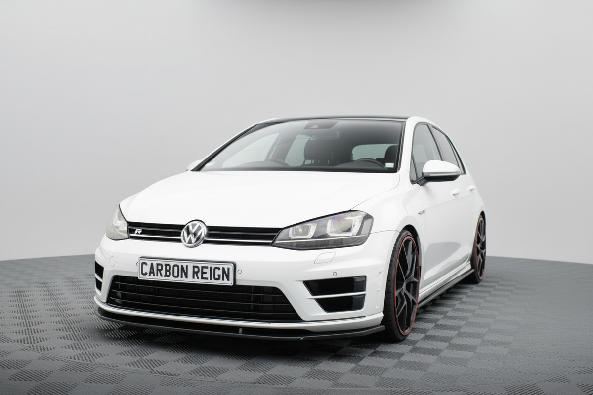 A white Volkswagen Golf R with a Carbon Reign performance lip kit on the front bumper, shown from a three-quarter angle on a gray checkered studio floor.
