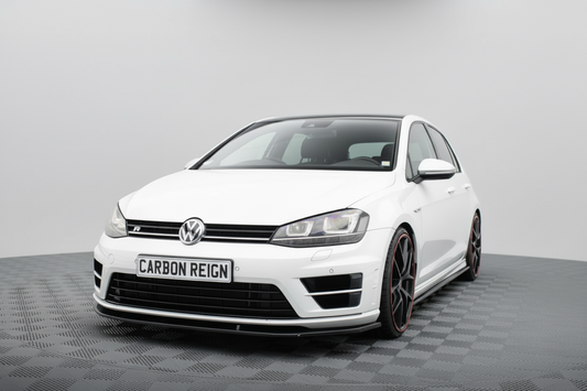 A white Volkswagen Golf R with a Carbon Reign performance lip kit on the front bumper, shown from a three-quarter angle on a gray checkered studio floor.