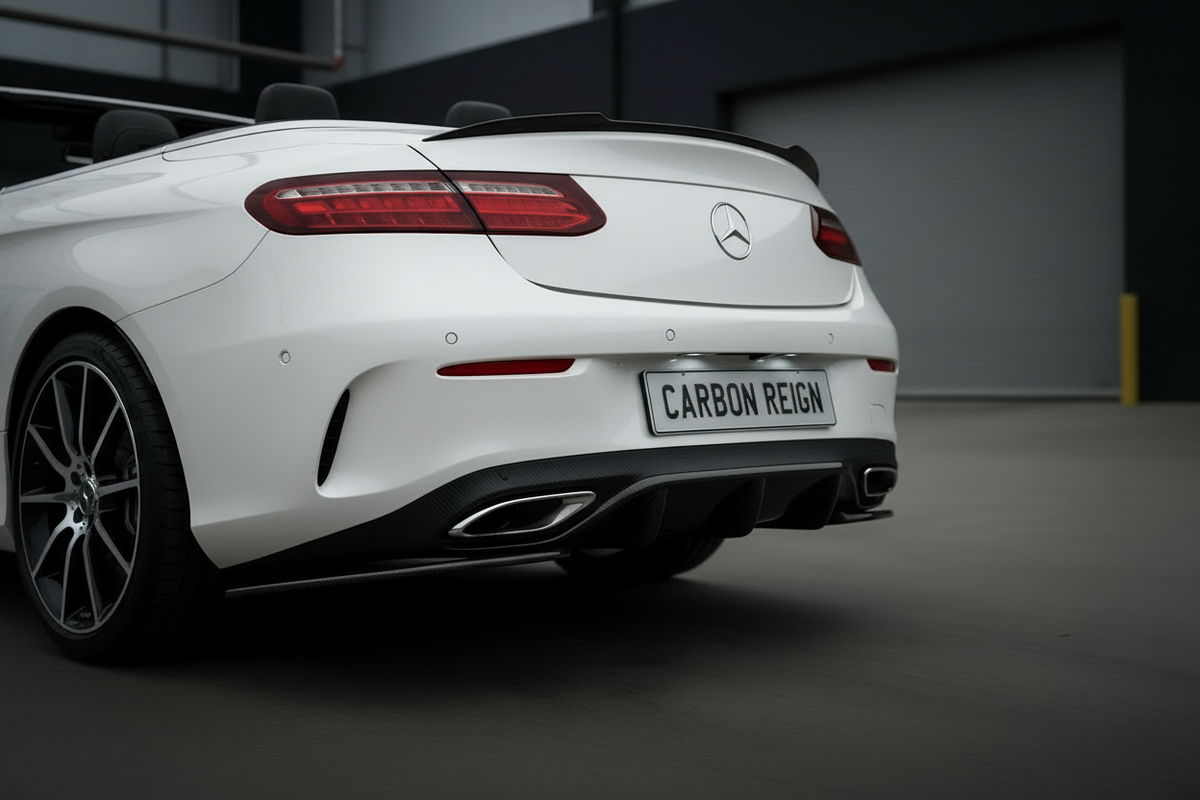 A white Mercedes-Benz Convertible with a red convertible top is parked outdoors in front of a dark gray industrial building with garage doors under a cloudy sky.