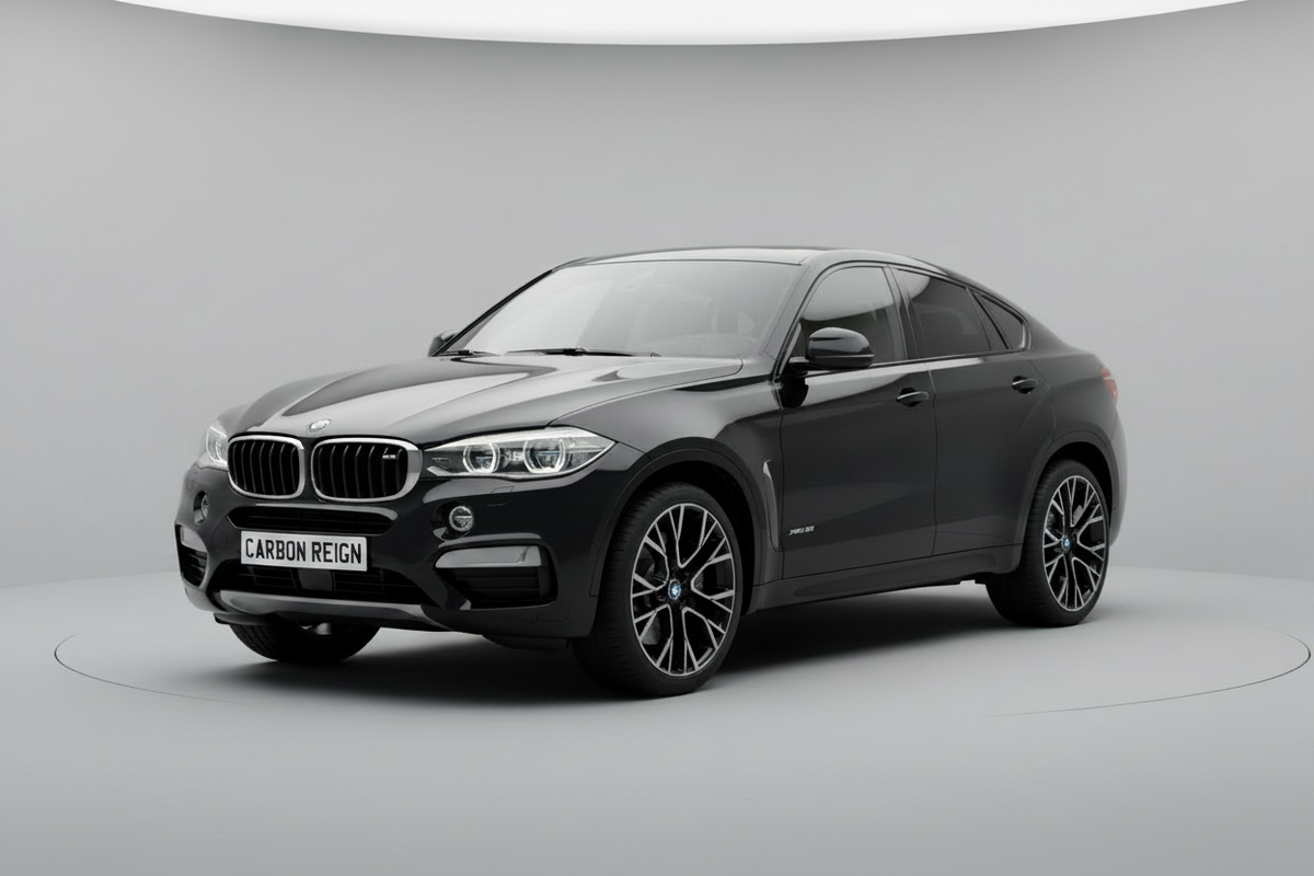 A dark gray BMW X6 M is shown in a three-quarter front view on a circular platform in a clean, modern studio setting with a light gray background.