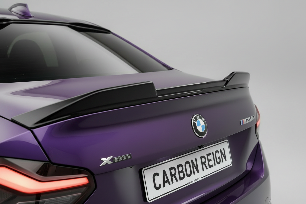 Close-up rear view of a purple BMW X5 M2 with a black carbon-fiber-look rear spoiler and a custom license plate reading 'CARBON REIGN' against a light gray studio background.