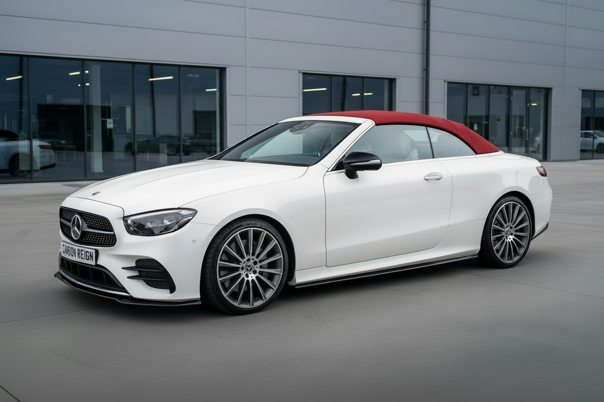 A white Mercedes-Benz A-Class convertible with a red soft top is parked outdoors in front of a modern gray building. The Mercedes-Benz logo is visible on the front grille.