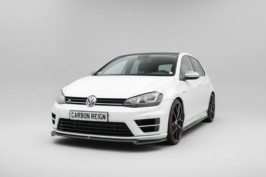 A white Volkswagen Golf R with a Carbon Reign carbon fiber front splitter and black multi-spoke wheels with red accents, photographed on a seamless light gray studio background.